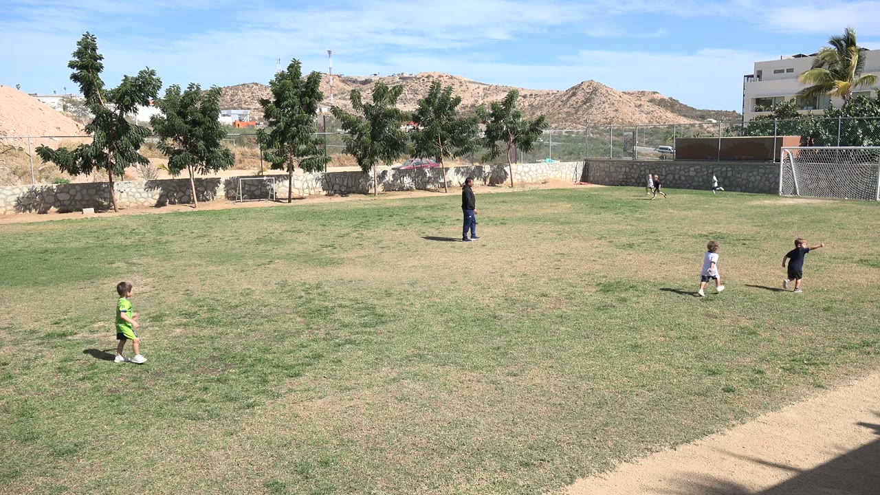 Children and a coach on a sunny football field.