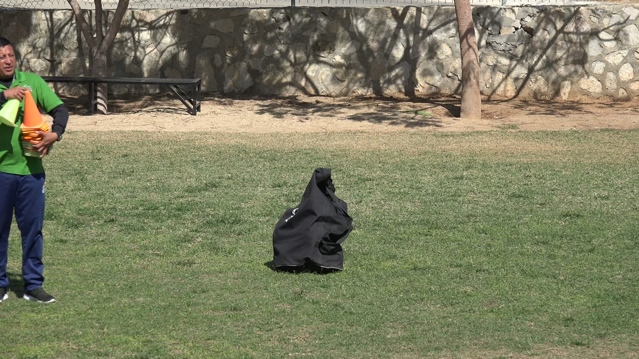 At the start of the Los Cabos, Mexico clip, a man is partly cropped at frame left while holding orange training cones near a black equipment bag on the grass.