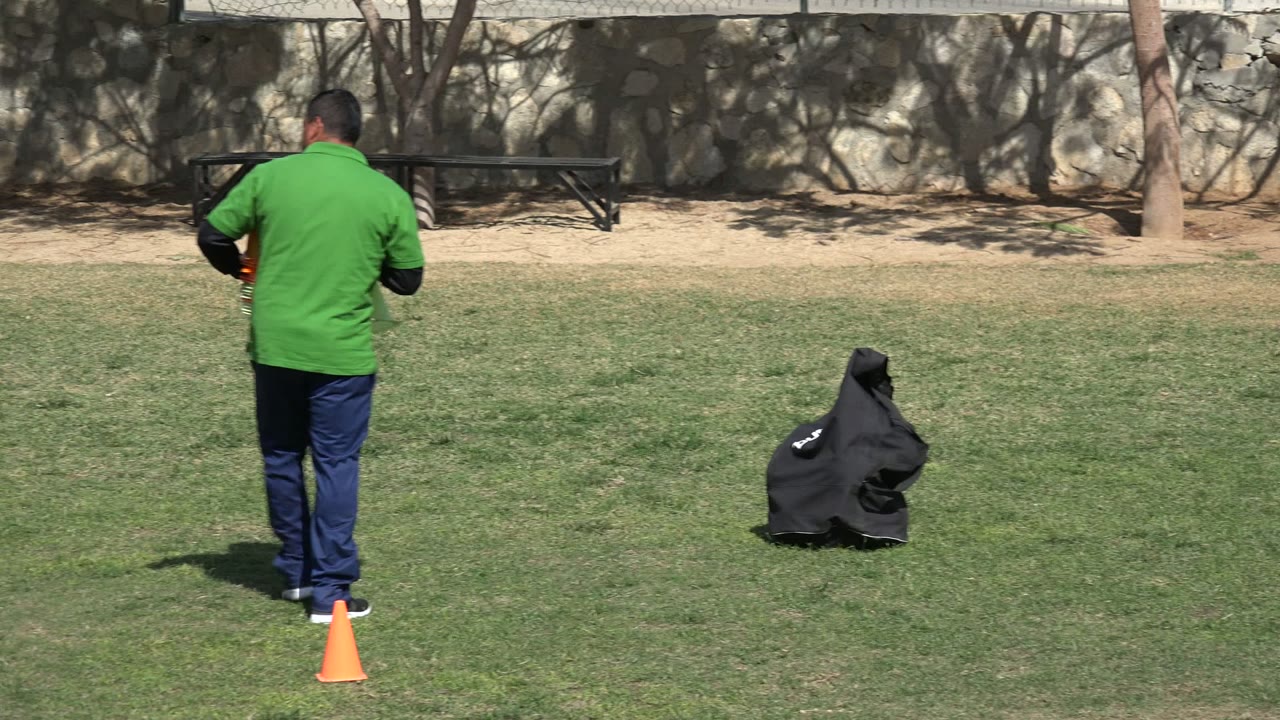 Coach standing near orange cone on grass field