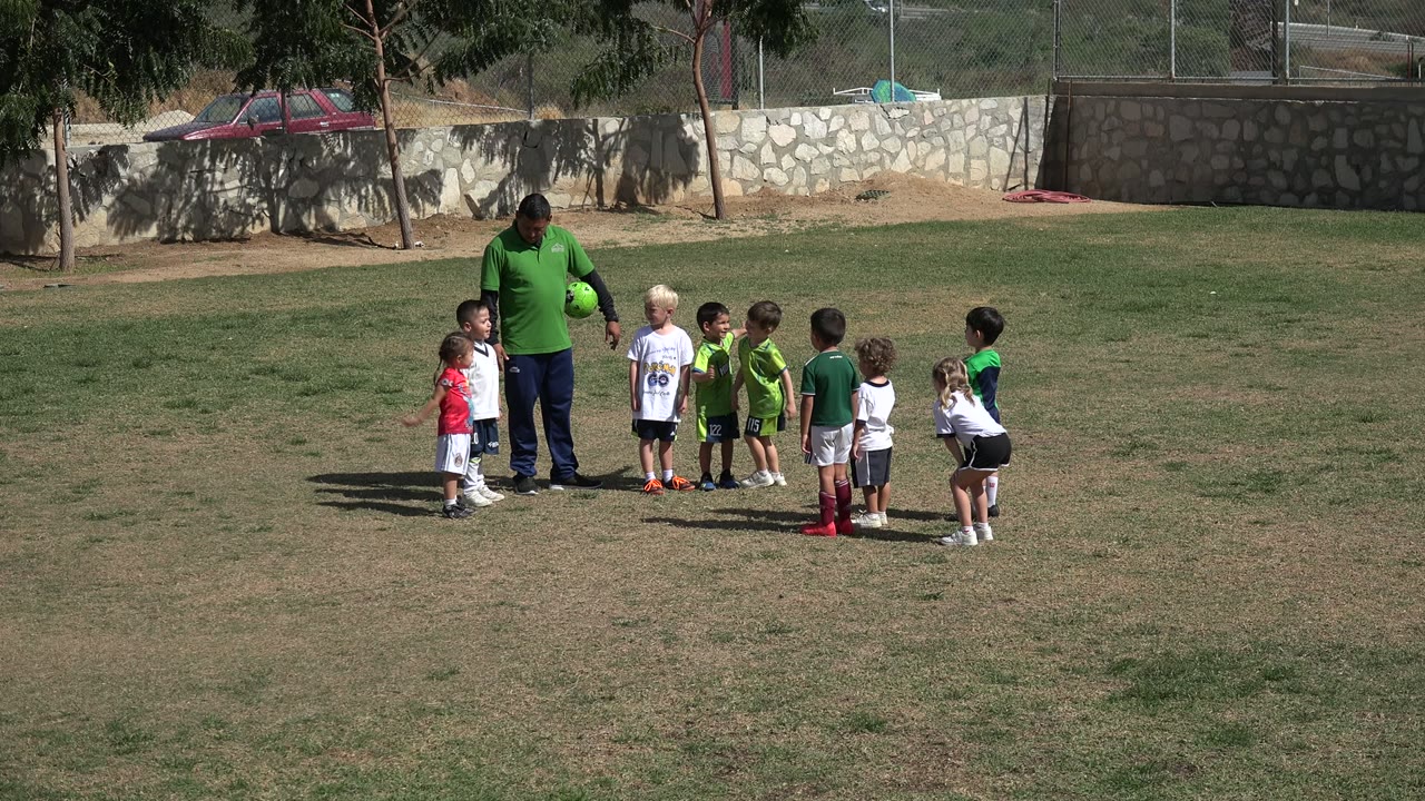 Adult man and children gathered on a soccer field.
