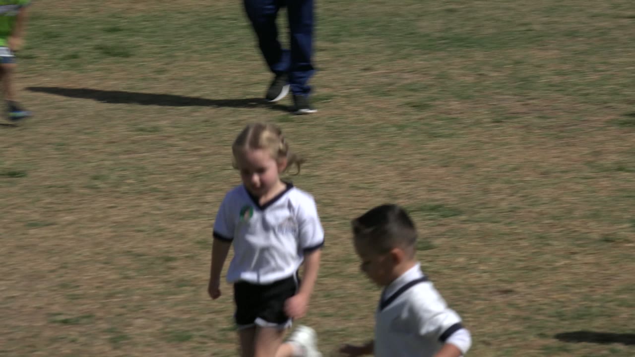 Children in soccer clothes running on a grass field