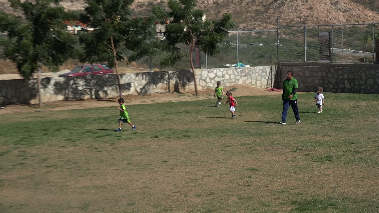 Children and an adult on a grassy field with dry hills behind them.