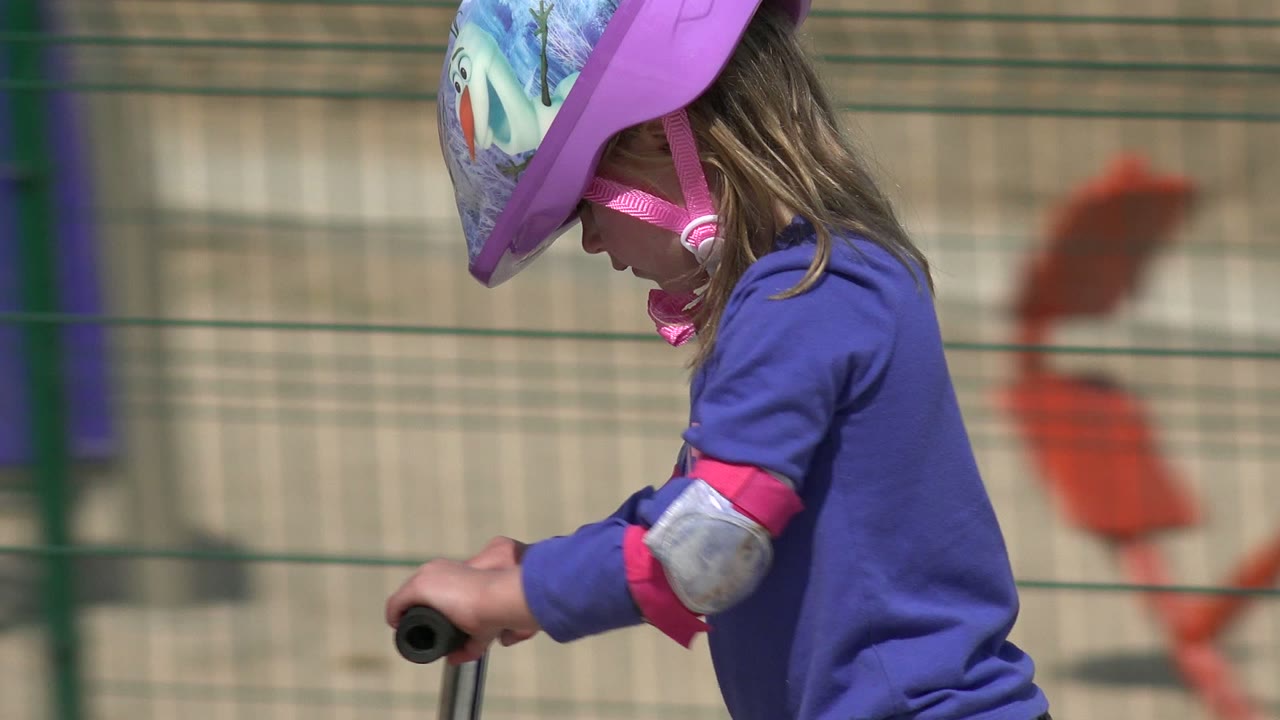 One second in, the girl is closer to center frame in Los Cabos, looking down toward the handlebars while wearing a purple helmet and gray elbow pad.