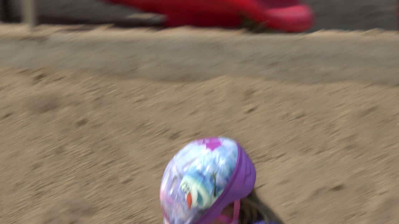 The helmeted child in Los Cabos, Mexico drops partly below the frame line as the tan dirt bank fills most of the view.