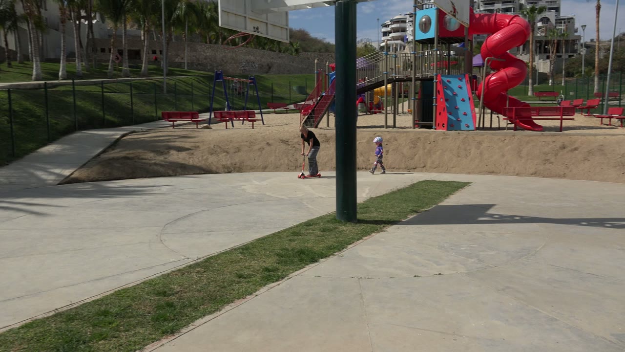 Child on scooter at right side of playground frame.