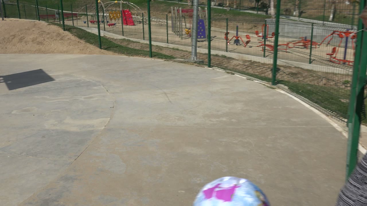 The frame looks across the empty concrete skate area in Los Cabos, Mexico, with the top of the child's purple helmet just visible at the lower edge.