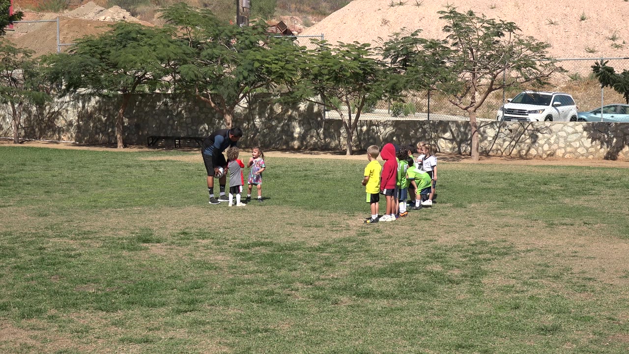 Coach and children gathered on a grassy field.