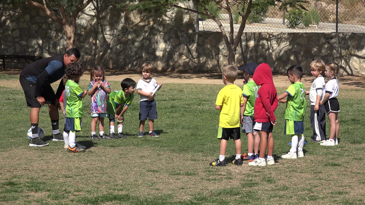 Coach and children gathered on a sunny grass field