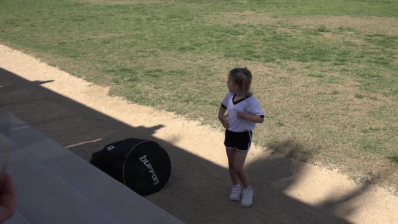Young girl standing on outdoor steps beside grass and a black gear bag.