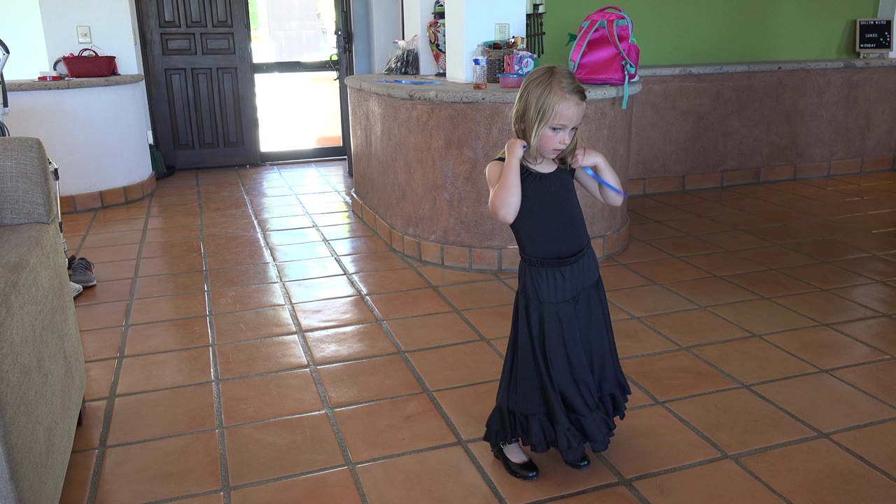Girl in black dress bringing a blue ribbon down near her shoulder.