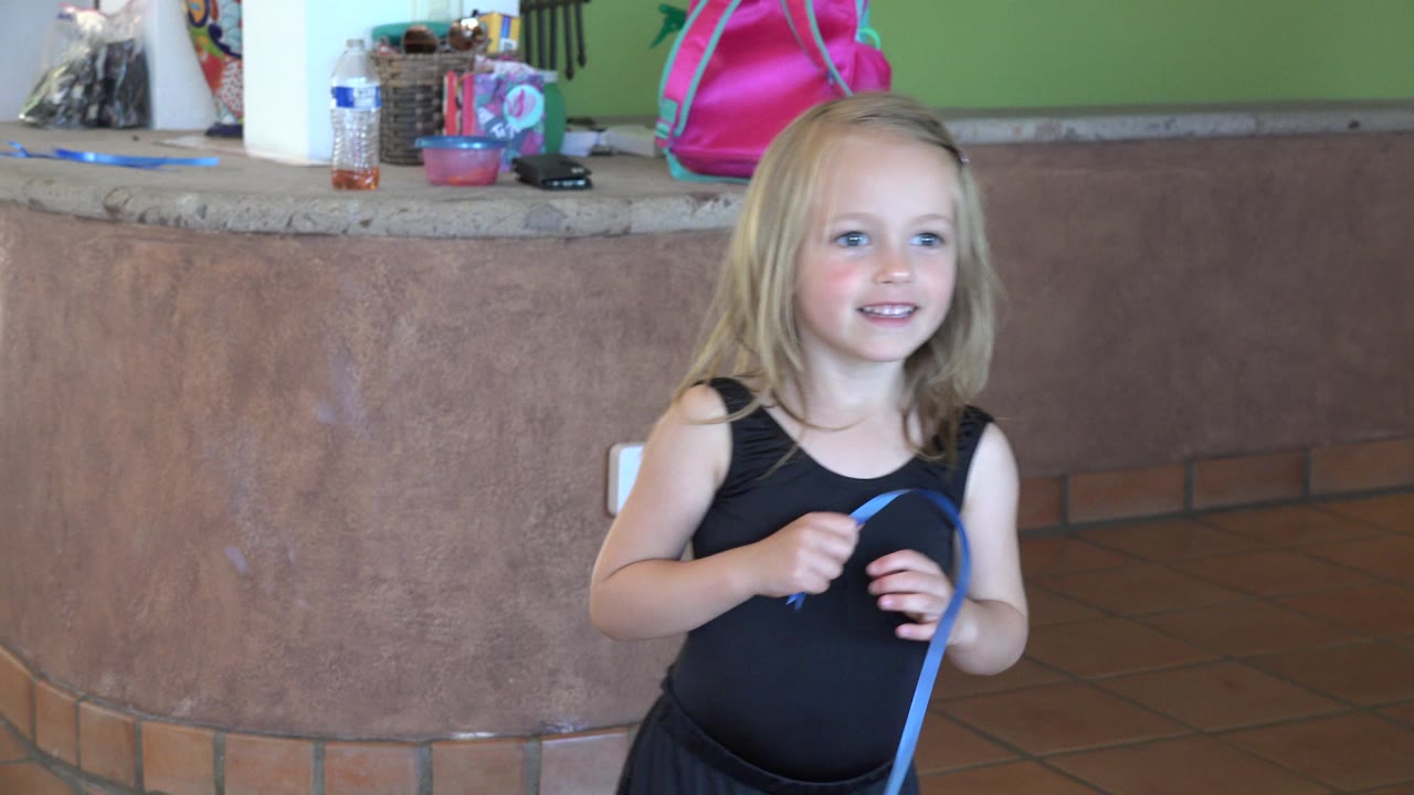 Young girl holding a blue rope indoors near a curved counter.