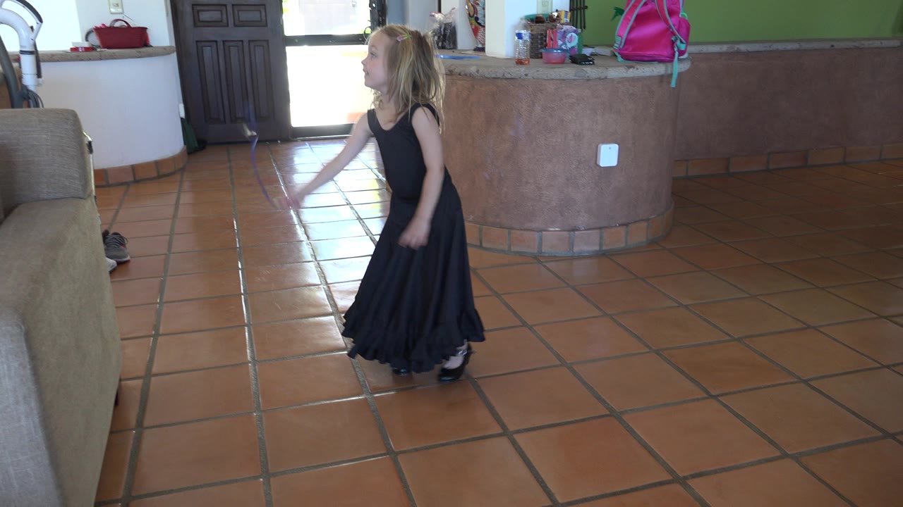 In Los Cabos, Mexico, the girl shifts her body left of center with the blue ribbon angled forward, framed by the couch and curved counter.
