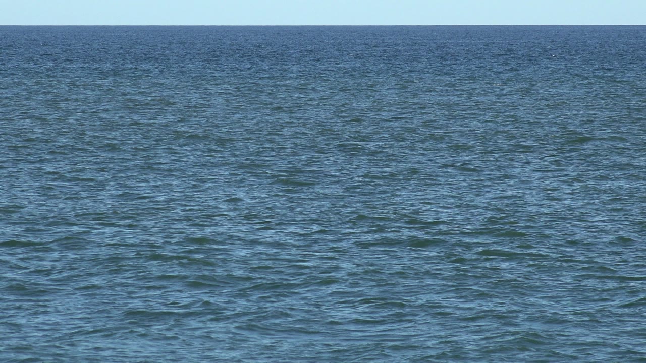 Los Cabos sea surface with fine wind ripples, darker blue water near the horizon, pale sky, and no visible people.