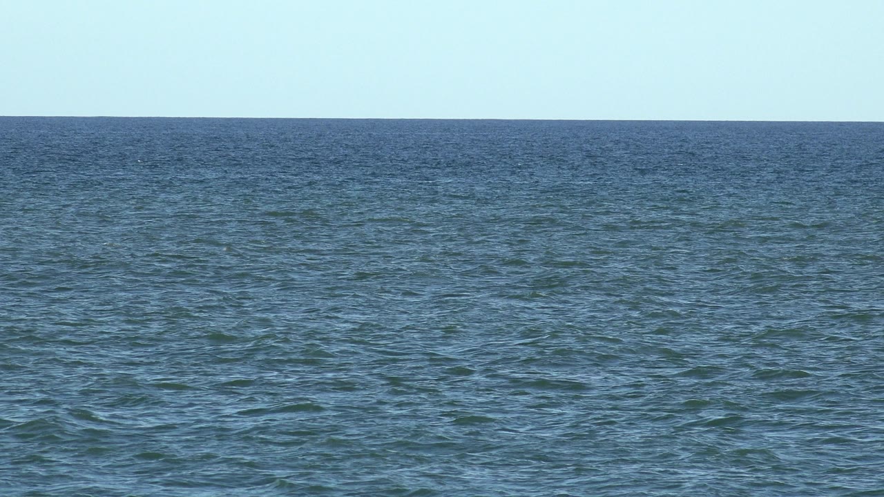 Wide view of blue-green ocean water and pale sky in Los Cabos, Mexico, with no visible people or boats.