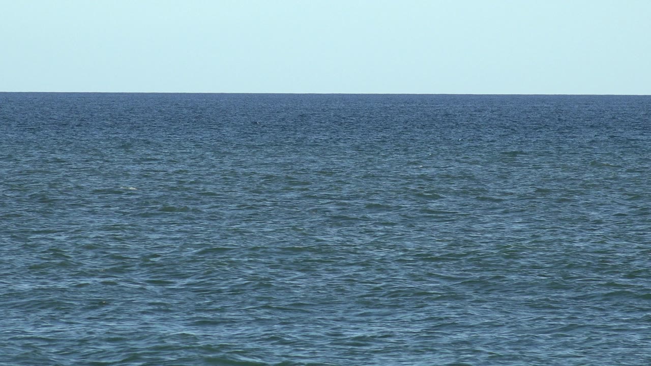 Opening frame of a Los Cabos ocean horizon with rippled blue water, pale sky, and no visible people.