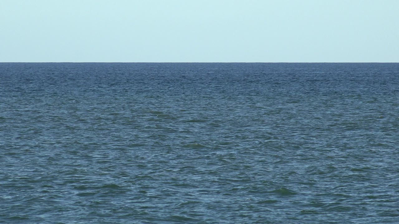 Blue-green ocean below a clear pale sky