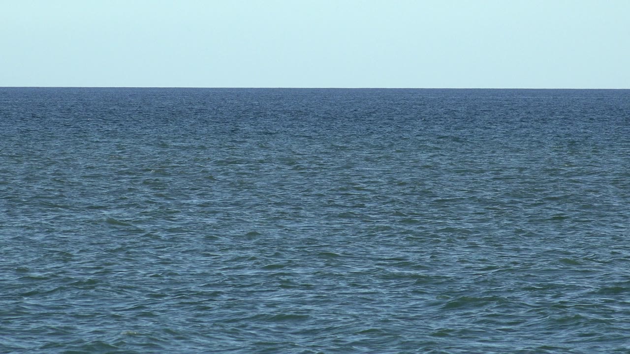 Wide blue ocean under a clear pale sky.