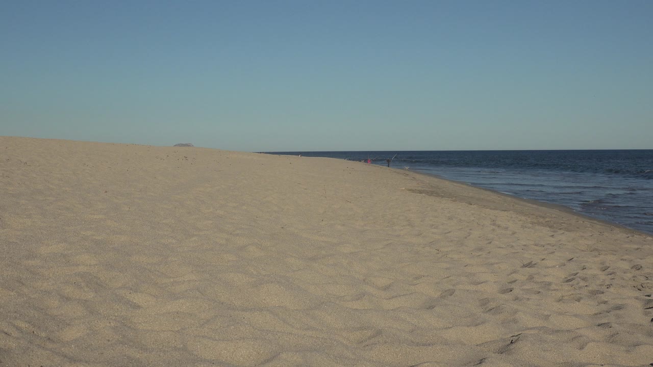 Open beach and calm ocean with sand tracks in the foreground.