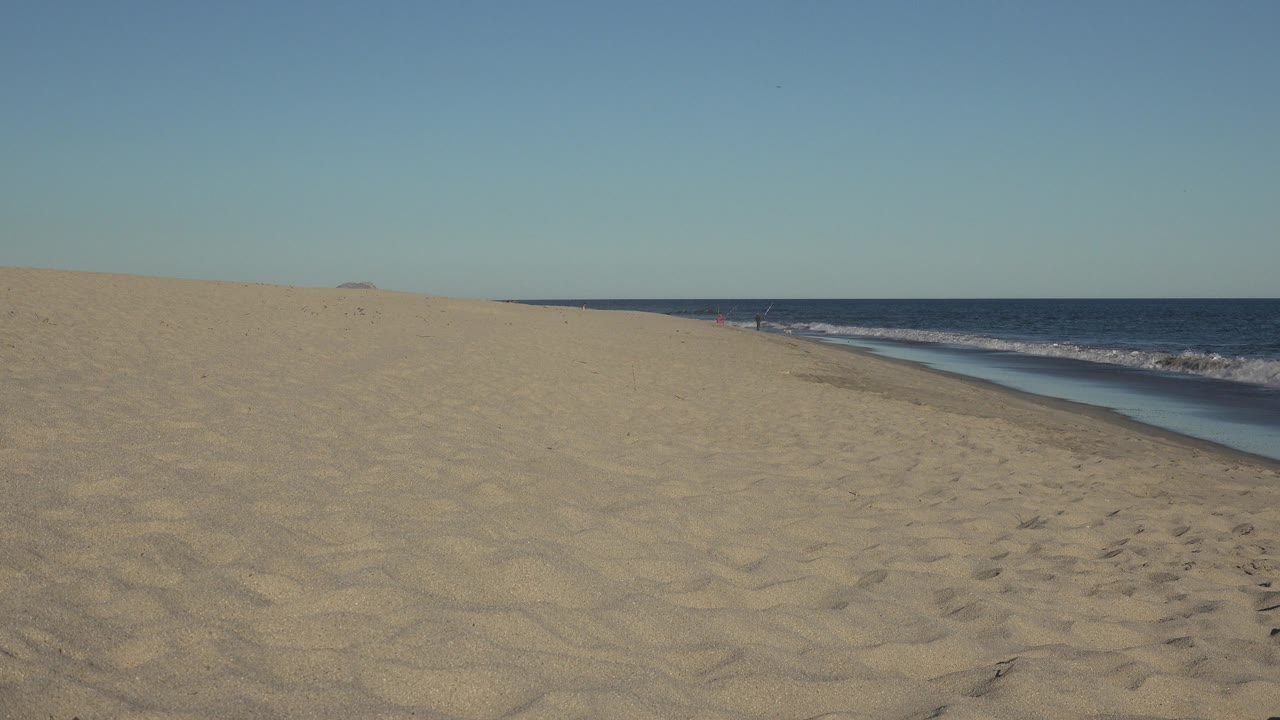 Empty beach slope beside dark blue ocean