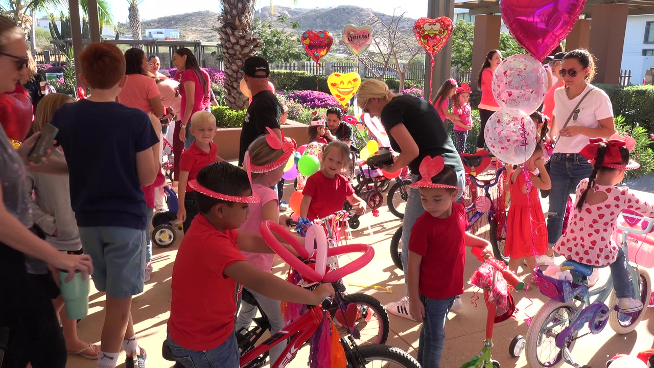 Children and adults at an outdoor party with balloons and bicycles.
