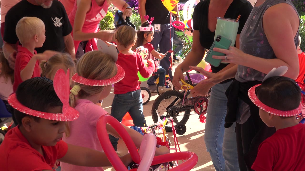 Children and adults gathered around small bikes at an outdoor party.