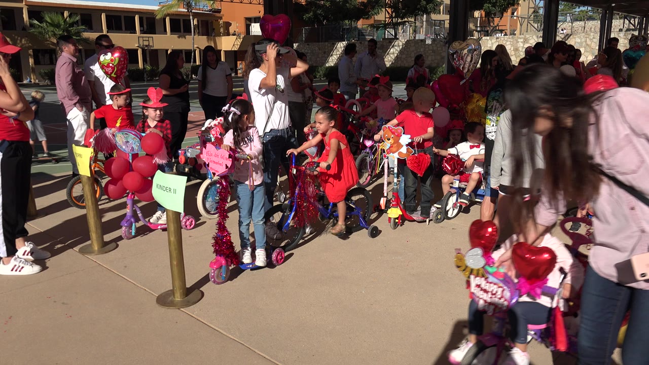 Children and adults gather beside decorated bikes and balloons on a sunny path.