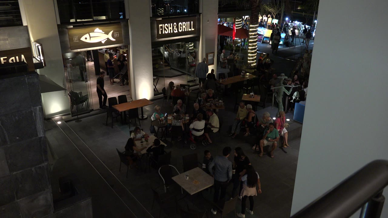 Elevated night view of outdoor food court tables and storefront signs.