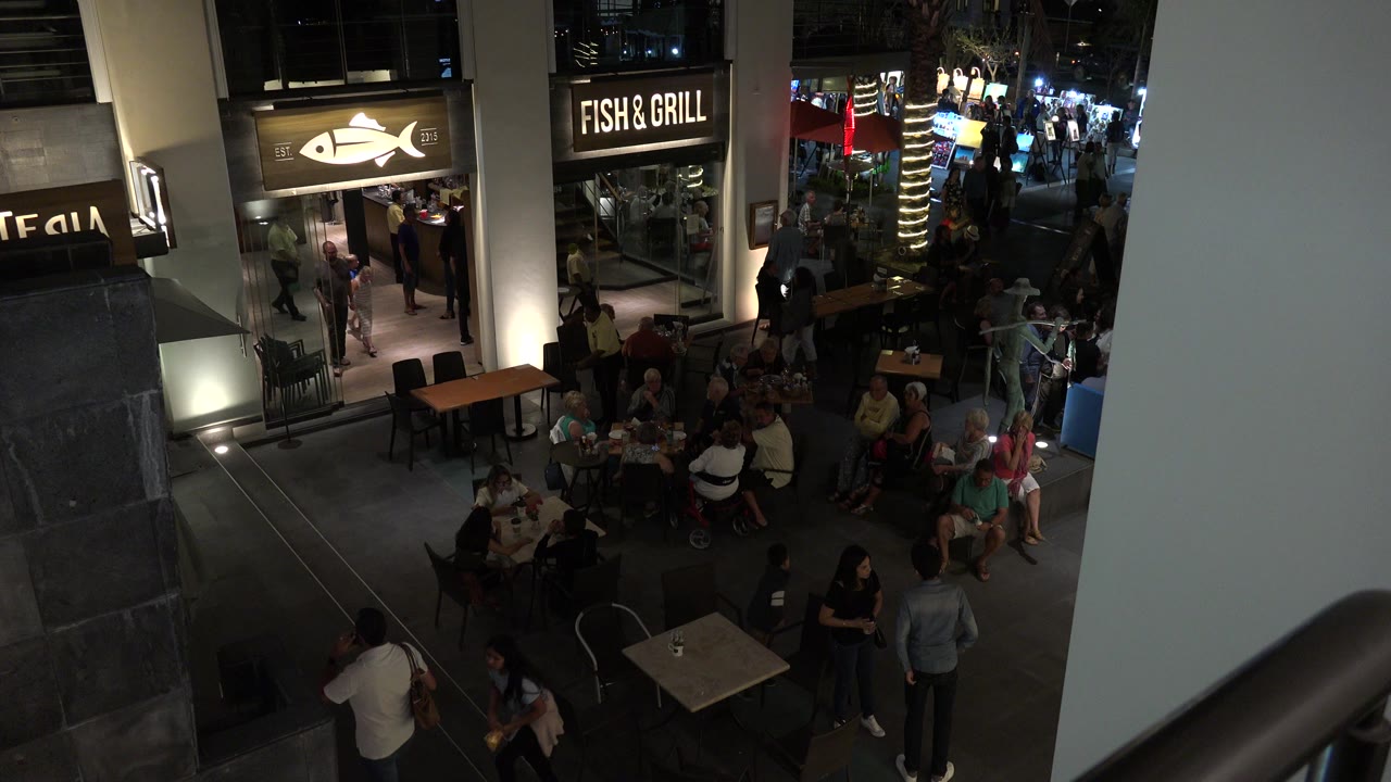 Elevated view of people outside a Fish & Grill storefront in a mall corridor.