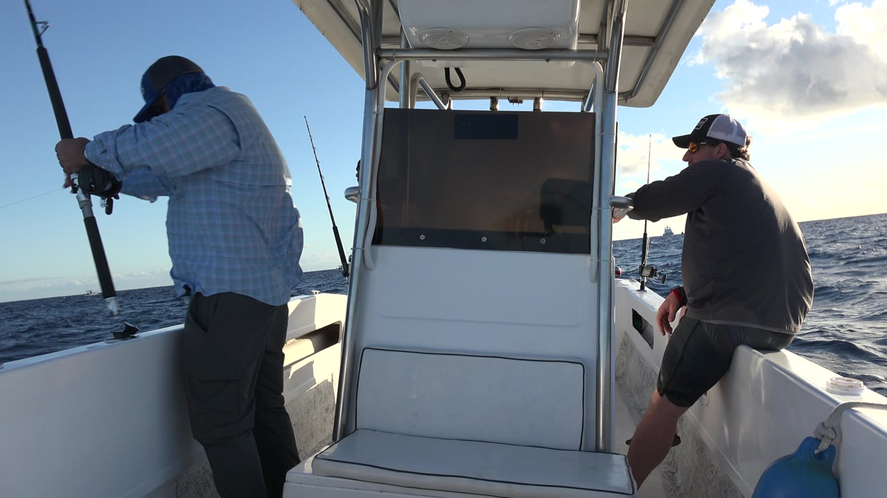 Two men fishing on a white boat at sea