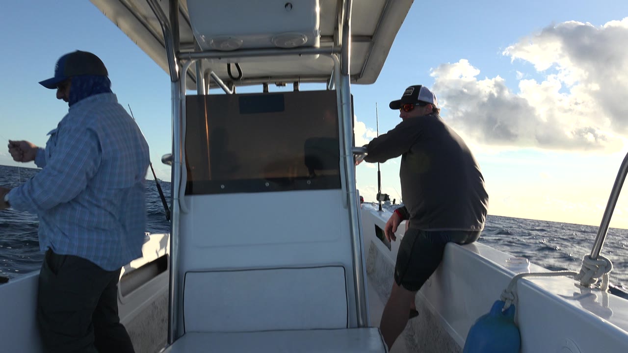 Two men fishing from a small boat on the ocean.