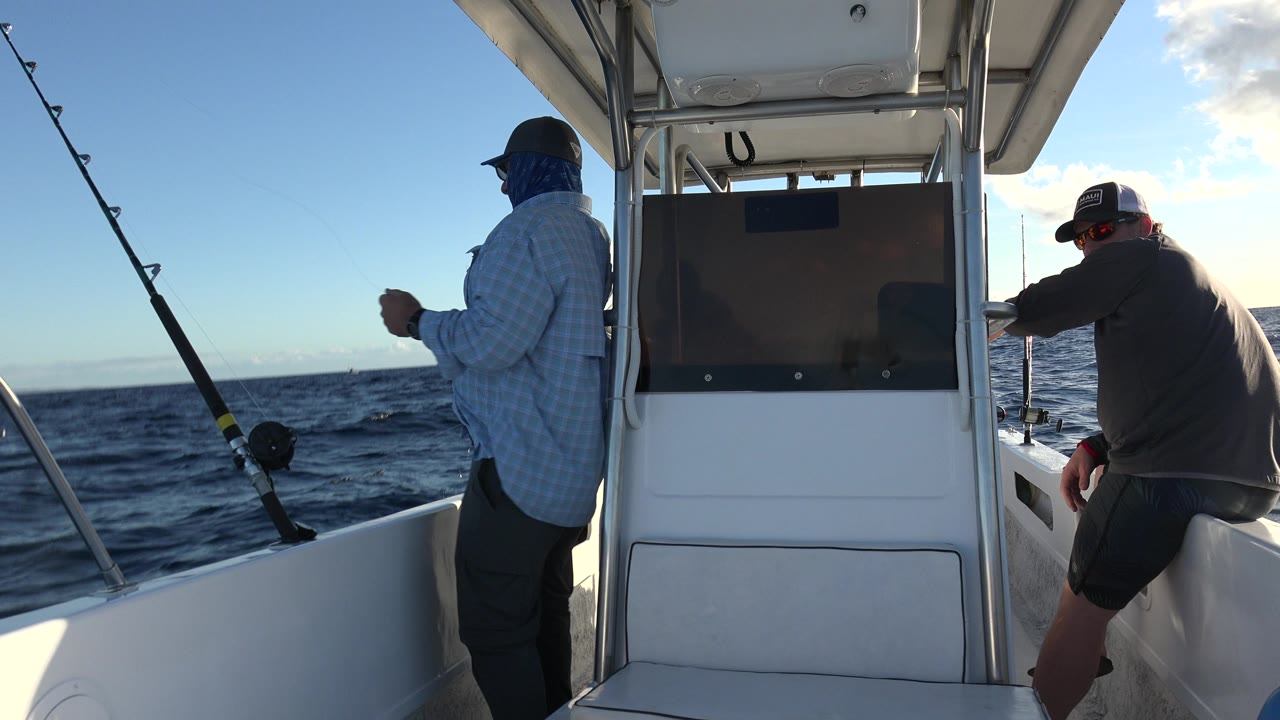 At the start of the Los Cabos clip, two adult men in caps are aboard a small fishing boat, with rods at the rail and dark ocean water behind them.