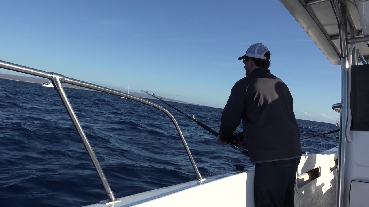 Man fishing from a white boat on open ocean.