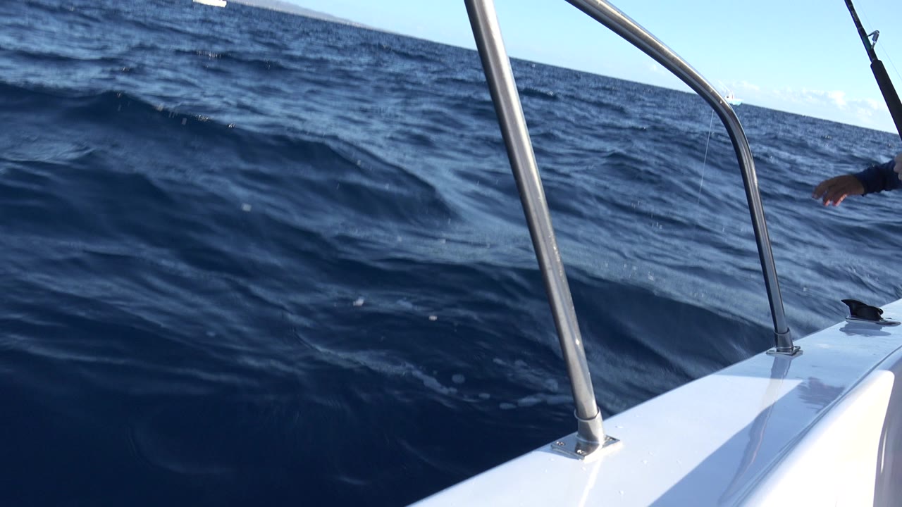 Boat bow rail over dark blue ocean waves.