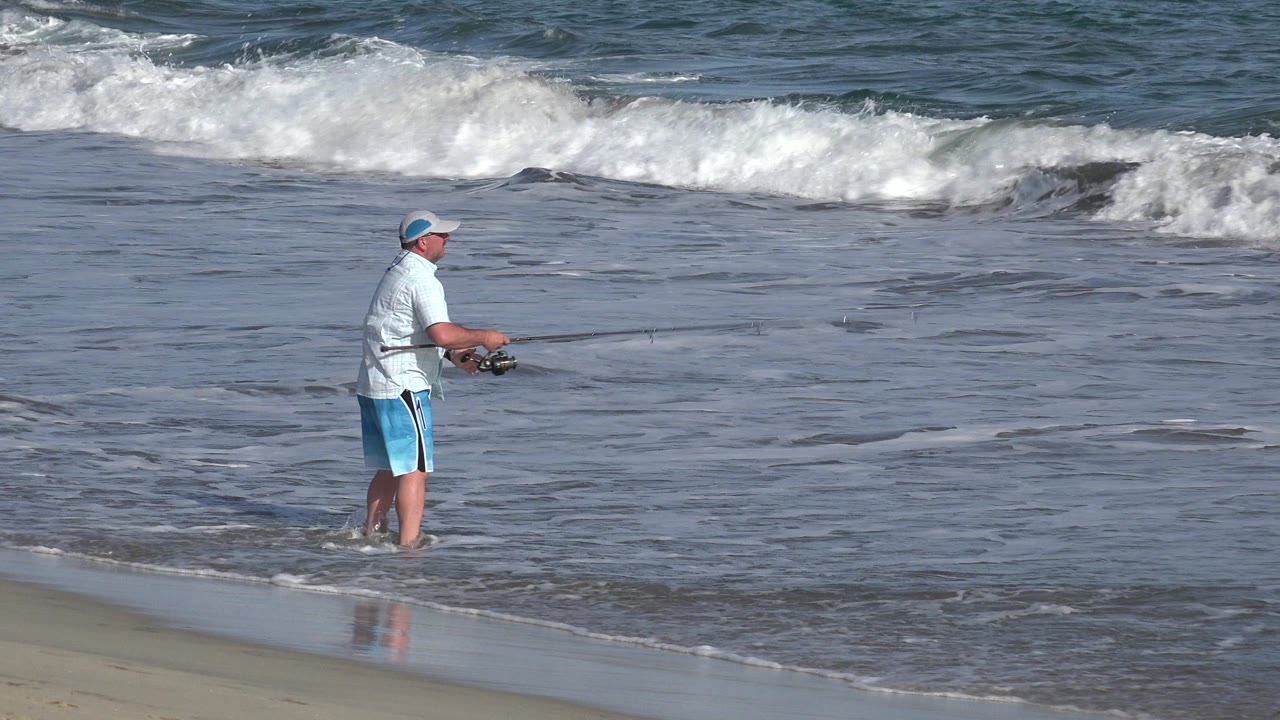 Man fishing alone at the edge of the surf.