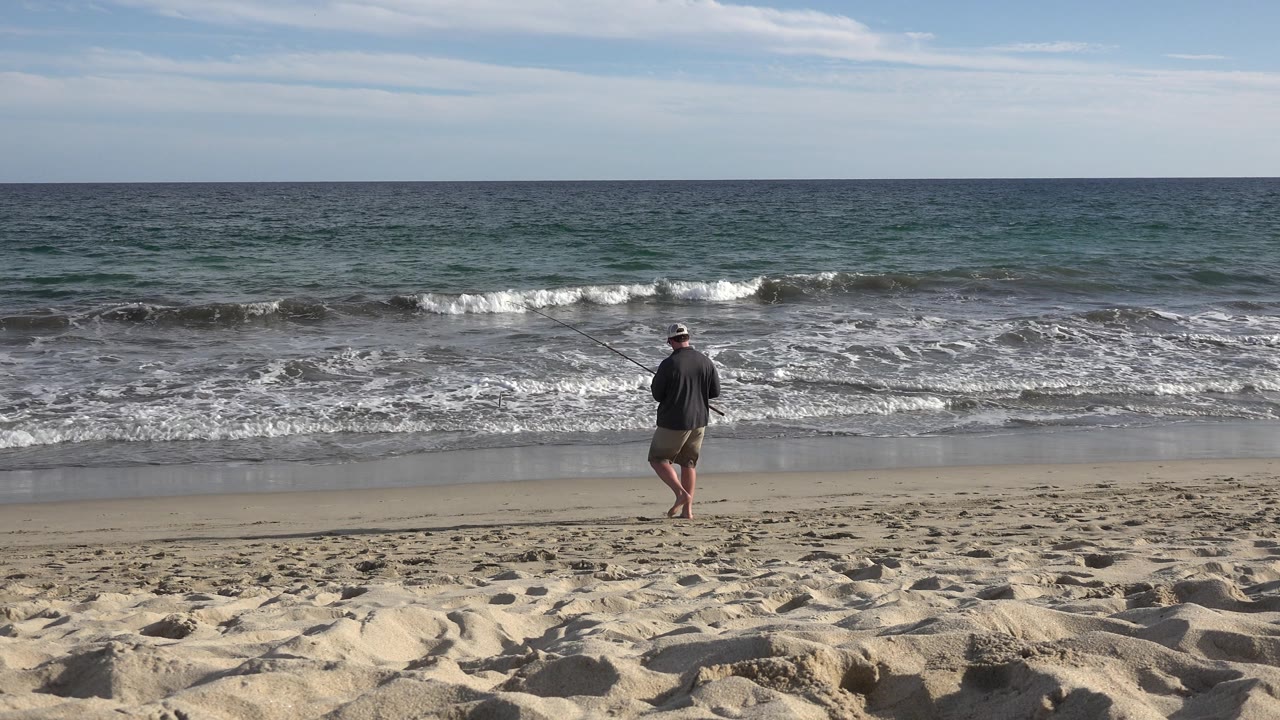 Man near shoreline with waves rolling in.