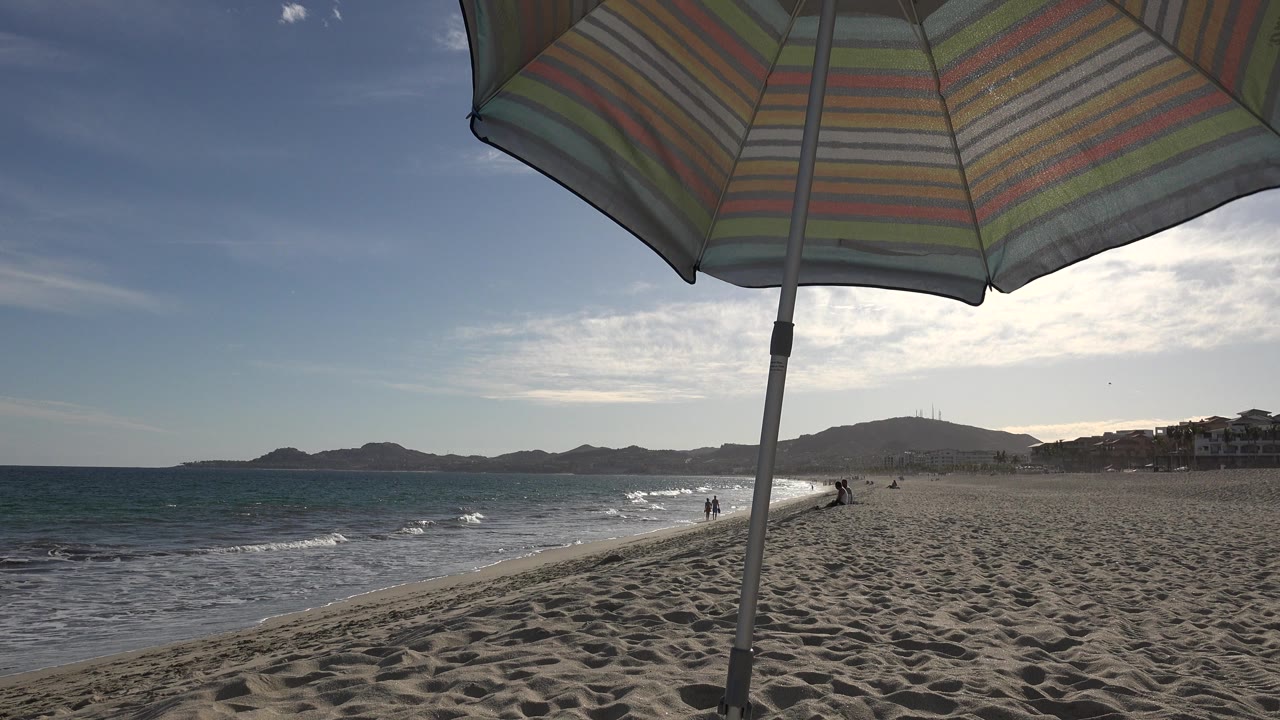 Striped beach umbrella over sand and ocean shoreline