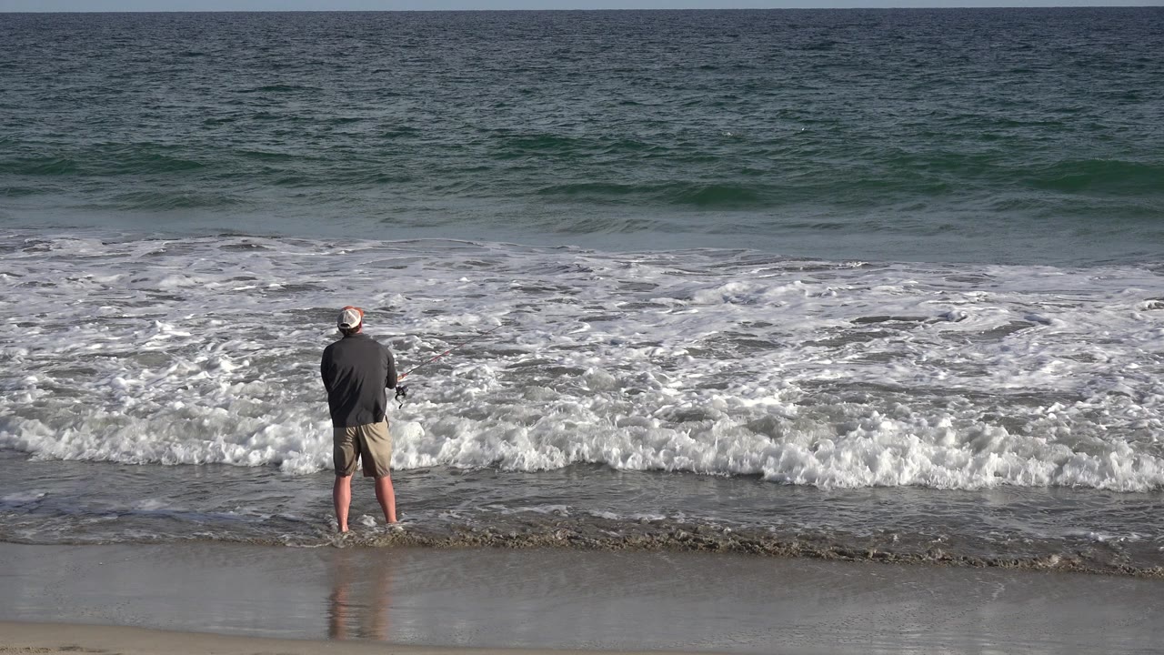 In Los Cabos, Mexico, the man remains centered near the waterline as foamy water washes over the darker wet sand in front of him.