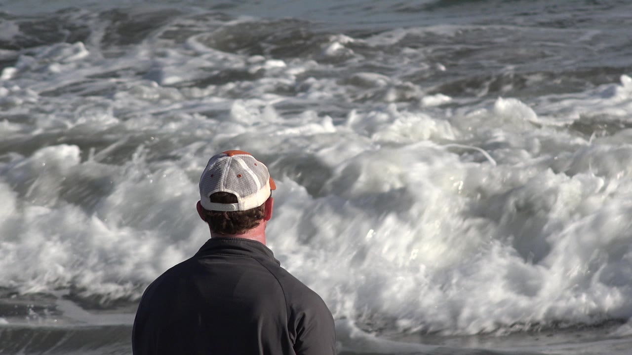 Man faces a closer line of churning surf.