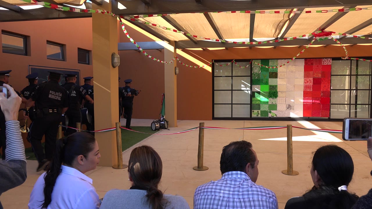 Police officers near an orange building as spectators watch from seats.
