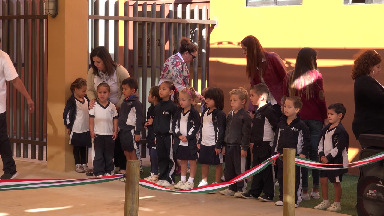 Children stand in a row while adults adjust and watch the group.