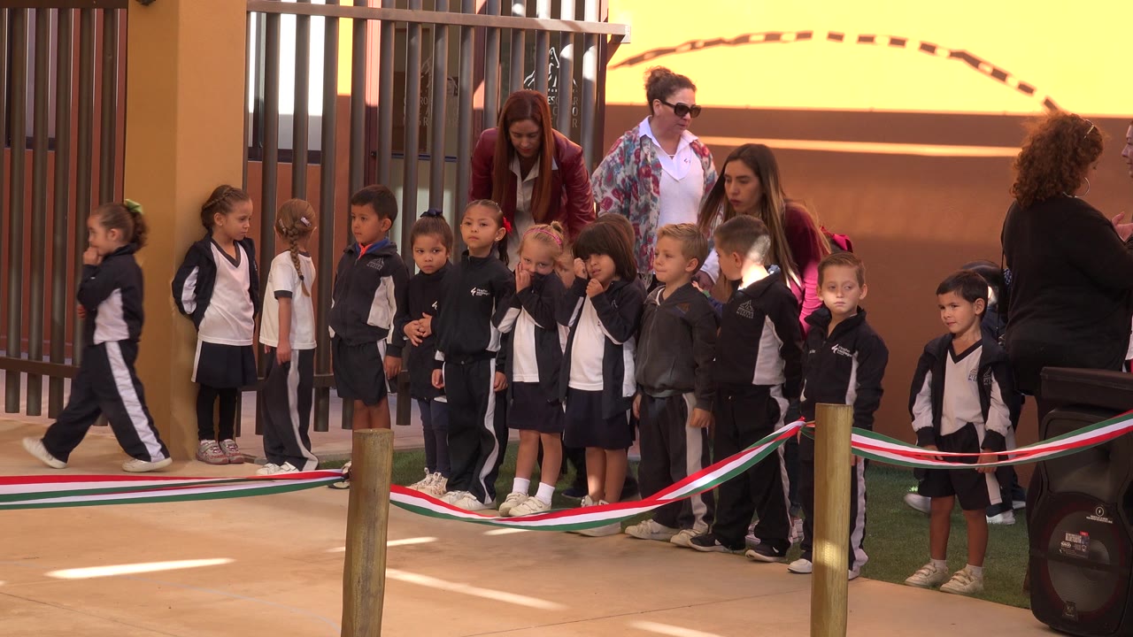 Adults stand behind a line of young schoolchildren.