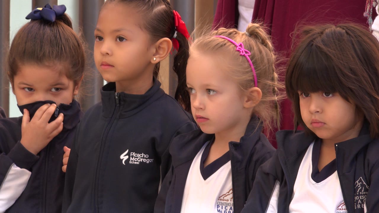 Four young girls stand together in navy-and-white tops.