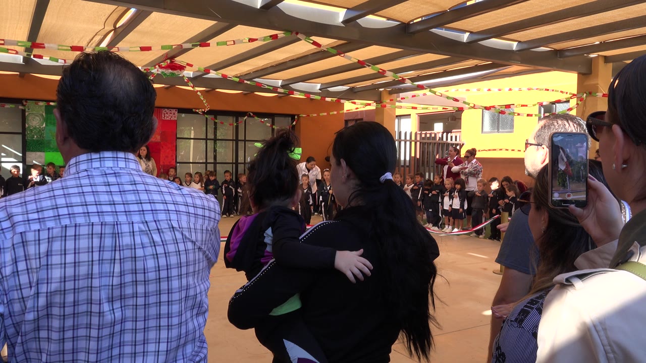 Adults watching children lined up in a courtyard