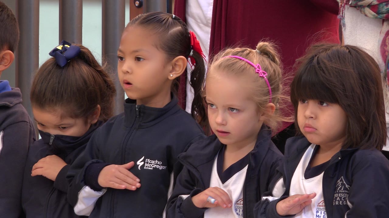 A group of girls in San Jose del Cabo, Mexico, remain lined up, with the central girl looking forward and a blonde child in a pink headband beside her.