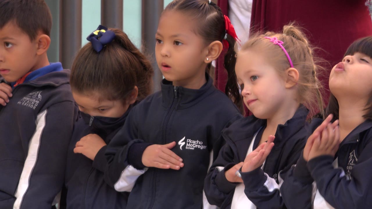 Young children in navy jackets standing close together.