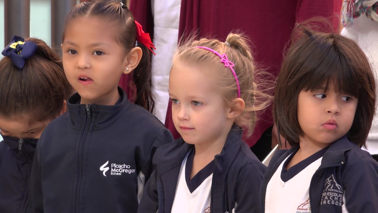 Three girls face forward and sideways in matching dark jackets.