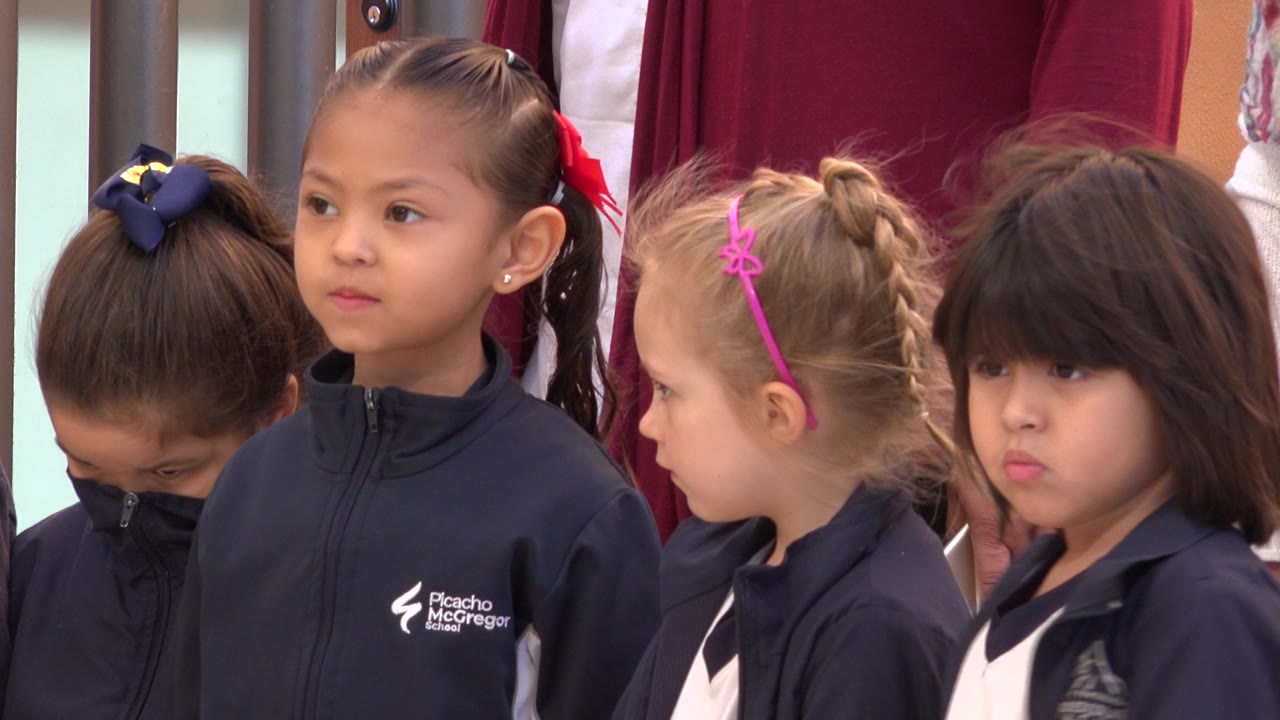 The group remains tightly framed in San Jose del Cabo, Mexico, with the left child looking down and the center girl facing forward beside two other girls.