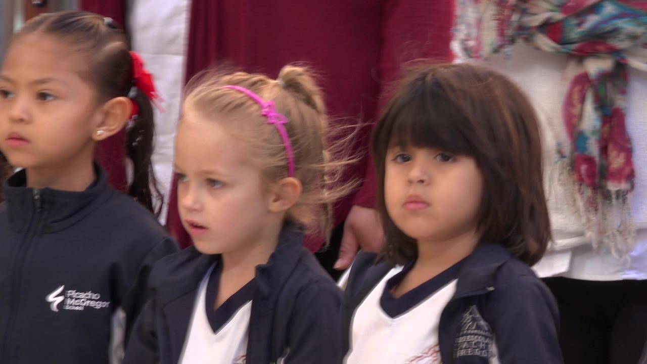 Three young girls in school uniforms look forward during the event.