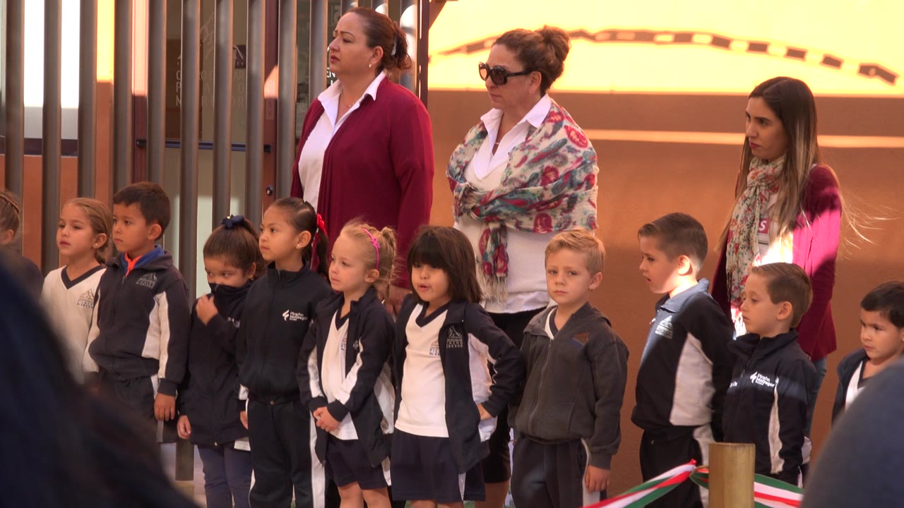 Children lined up for a school recital with adults standing behind them.