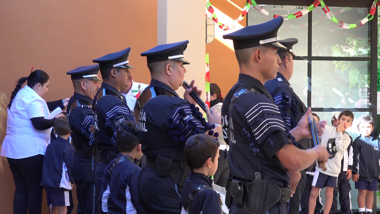Police officers stand beside children at a daytime ceremony.